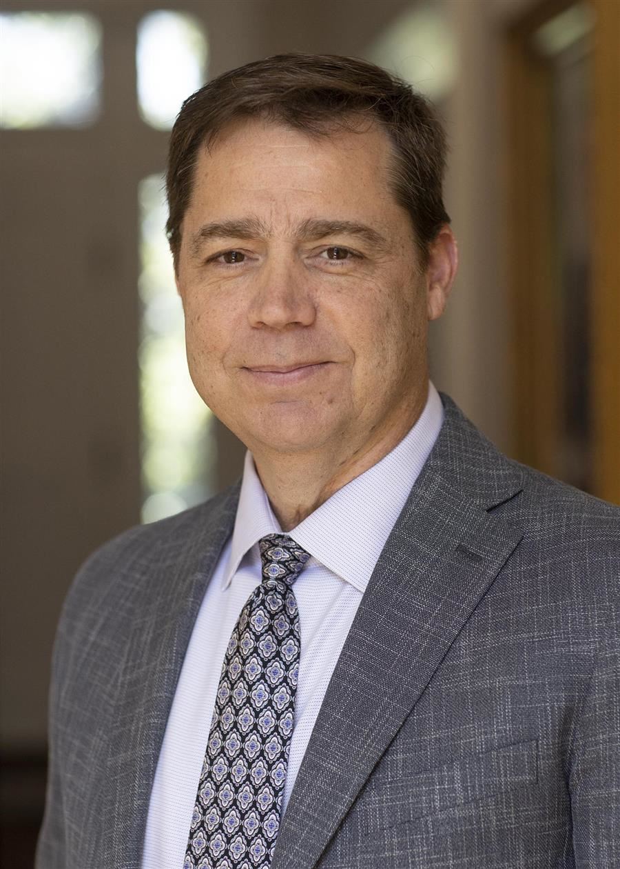  Dennis Gilliam smiles to camera while wearing a gray suit. 